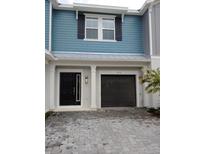 Exterior of a charming townhome with a dark gray garage door and light gray stone driveway at 2878 Grand Kemerton Pl, Tampa, FL 33618