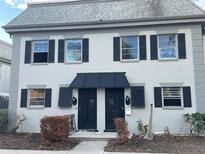 Two-story duplex with gray siding, black shutters, and a black awning at 1151 Rue Des Chateaux, St Petersburg, FL 33707