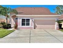 Two-story house with a two-car garage, light pink exterior, and neatly landscaped lawn at 1218 Vinetree Dr, Brandon, FL 33510