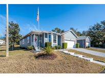 House exterior featuring a gray color scheme, landscaping, and a two-car garage at 37443 Blueberry Ct, Zephyrhills, FL 33542