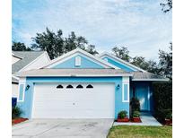 Curb appeal abounds at this charming light blue house with a white door and two car garage at 8434 Hawbuck St, Trinity, FL 34655