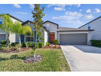 Single-story home with gray siding, orange door and attached garage at 4654 Wild Senna Blvd, Tampa, FL 33619