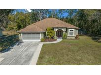 Single-story house with a two car garage and a well maintained lawn at 628 Erin Way, Brooksville, FL 34601