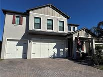 Two-story home with three-car garage, paver driveway, and landscaped front yard at 8365 Capstone Ranch Dr, New Port Richey, FL 34655