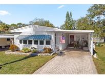 White single-wide manufactured home with covered carport and landscaped yard at 9790 66Th N St # 130, Pinellas Park, FL 33782