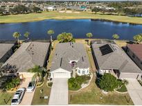 Aerial view of a house with a lake and golf course in the background at 1031 Emerald Dunes Dr, Sun City Center, FL 33573