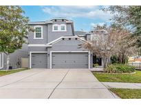 Two-story house with gray siding, two-car garage, and landscaping at 10409 Waterstone Dr, Riverview, FL 33578