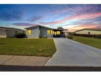 Sunset view of a manufactured home with carport and landscaped lawn at 37622 New Horizons Blvd, Zephyrhills, FL 33541