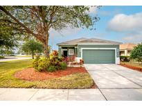 Green house with two-car garage and landscaped yard at 7241 Forest Mere Dr, Riverview, FL 33578