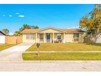 Brick ranch house with a covered porch, driveway, and well-maintained lawn at 8348 Garrison Cir, Tampa, FL 33615