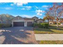 Two-car garage, paver driveway, manicured lawn, and attractive landscaping at 2564 Grand Cypress Blvd, Palm Harbor, FL 34684