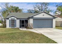One-story house with gray garage door and well-maintained lawn at 1628 Baker Rd, Lutz, FL 33559