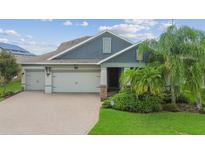 Two-story home with gray siding, three-car garage, and landscaped yard at 18992 Roseate Dr, Lutz, FL 33558