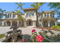 Stately two-story home featuring a grand entrance, fountain, lush landscaping and elegant architectural details at 26 Sunset Bay Drive, Belleair, FL 33756
