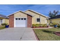 Cute yellow house with a brick accent and a two-car garage at 37347 Derbyshire Dr, Zephyrhills, FL 33542