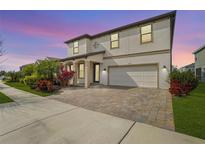 Two-story house with a white facade, paver driveway, and landscaping at 4062 Cadence Loop, Land O Lakes, FL 34638
