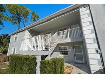 Gray two-story building with white railings and landscaping at 7713 Hillside Ct # 201, Hudson, FL 34667