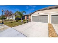 Tan house with gray two-car garage, landscaping, and driveway at 13987 Weddington Ter, Hudson, FL 34669