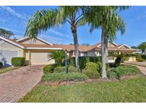Tan colored exterior, two-car garage, and lush landscaping at 2405 New Haven Cir, Sun City Center, FL 33573