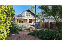 Charming two-story home featuring a brick pathway, lush landscaping, and a cozy front porch with ornate yellow trim at 2445 3Rd N Ave, St Petersburg, FL 33713