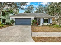Cute one-story house with gray garage door, screened porch, and landscaped yard at 2517 Wrencrest Cir, Valrico, FL 33596