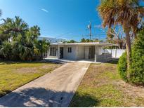 Single-story home with driveway, landscaping, and tropical plants at 812 Bohenia N Cir, Clearwater Beach, FL 33767
