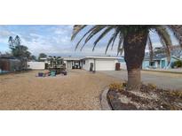 Single-story home with a gravel front yard, palm tree, and white fence at 10128 Paradise Blvd, Treasure Island, FL 33706