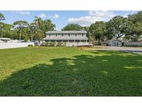 Large grassy yard with mature trees and a two-story house at 1055 Philippe Pkwy, Safety Harbor, FL 34695