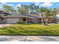 Brick ranch home with attached garage and lush lawn at 14926 Lake Forest Dr, Lutz, FL 33559