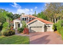 Two-story house with a three-car garage and lush landscaping at 1598 Lockmeade Pl, Oldsmar, FL 34677