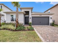 One-story home with gray exterior, two-car garage, and landscaped front yard at 3433 Great Banyan Way, Wesley Chapel, FL 33543