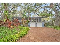 Mid-century modern home with lush landscaping and a two-car garage at 751 Pinellas Point S Dr, St Petersburg, FL 33705