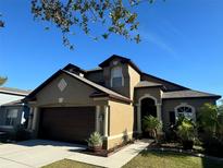Two-story house with brown garage door and landscaping at 8103 Tar Hollow Dr, Gibsonton, FL 33534