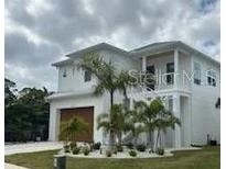 Two-story house with white exterior, brown garage door, and landscaping at 1840 Douglas Ave, Dunedin, FL 34698