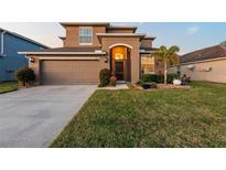 Two-story house with tan exterior, two-car garage, and landscaped lawn at 2307 Dakota Rock Dr, Ruskin, FL 33570