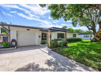 Inviting home exterior featuring a covered entryway, well-manicured lawn, and a two-car garage at 8532 Kumquat Ave, Seminole, FL 33777