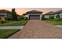 Charming home featuring a tile roof, a brick driveway, a two-car garage, and manicured landscaping at 11125 Callisia Dr, Odessa, FL 33556