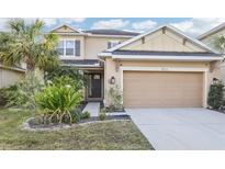 Two-story house with beige exterior, landscaped lawn, and two-car garage at 8836 Citrus Palm Dr, Tampa, FL 33626