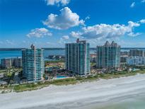 An aerial view showcasing beachfront condos with a pool, tennis courts, and ocean views at 1520 Gulf Blvd # 1602, Clearwater Beach, FL 33767
