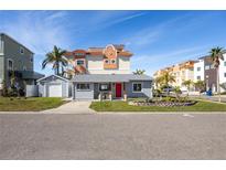 Gray house with red door, landscaping, and driveway; located in a neighborhood with other houses at 189 175Th E Ave, Redington Shores, FL 33708