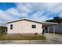 Pink mobile home with carport and landscaping at 275 Pelican Dr N, Oldsmar, FL 34677
