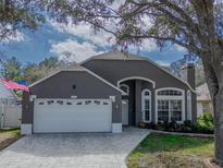 Gray house with white garage door, landscaping, and a paved driveway at 4932 Ridgemoor Cir, Palm Harbor, FL 34685