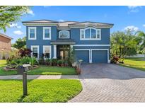 Two-story house featuring a blue exterior, paved driveway, and manicured landscaping at 12833 Darby Ridge Dr, Tampa, FL 33624
