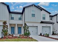 Two-story townhome with gray siding, two-car garage, and landscaped front yard at 31424 Amberview Bend, Wesley Chapel, FL 33545