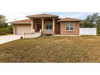 Single-story home with a tan stucco exterior, a large front yard, and a two-car garage at 3391 Knox Ter, Port Charlotte, FL 33948