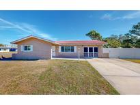 Brick ranch house with red tile roof, driveway, and well-maintained lawn at 7499 7Th N St, St Petersburg, FL 33702