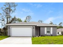 Newly constructed home with gray siding, white garage door, and a well-manicured lawn at 7849 Grafton Rd, North Port, FL 34291