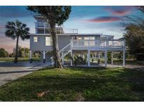 Charming stilt home featuring a large deck, lush greenery, and tropical landscaping at 3476 Tidewater Dr, Weeki Wachee, FL 34607