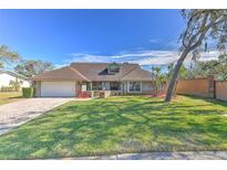 Attractive single-story home with landscaped lawn and brick driveway at 3500 Landmark Trl, Palm Harbor, FL 34684