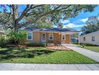 Tan house with covered porch, landscaped yard, and a driveway at 5042 8Th St, Zephyrhills, FL 33542